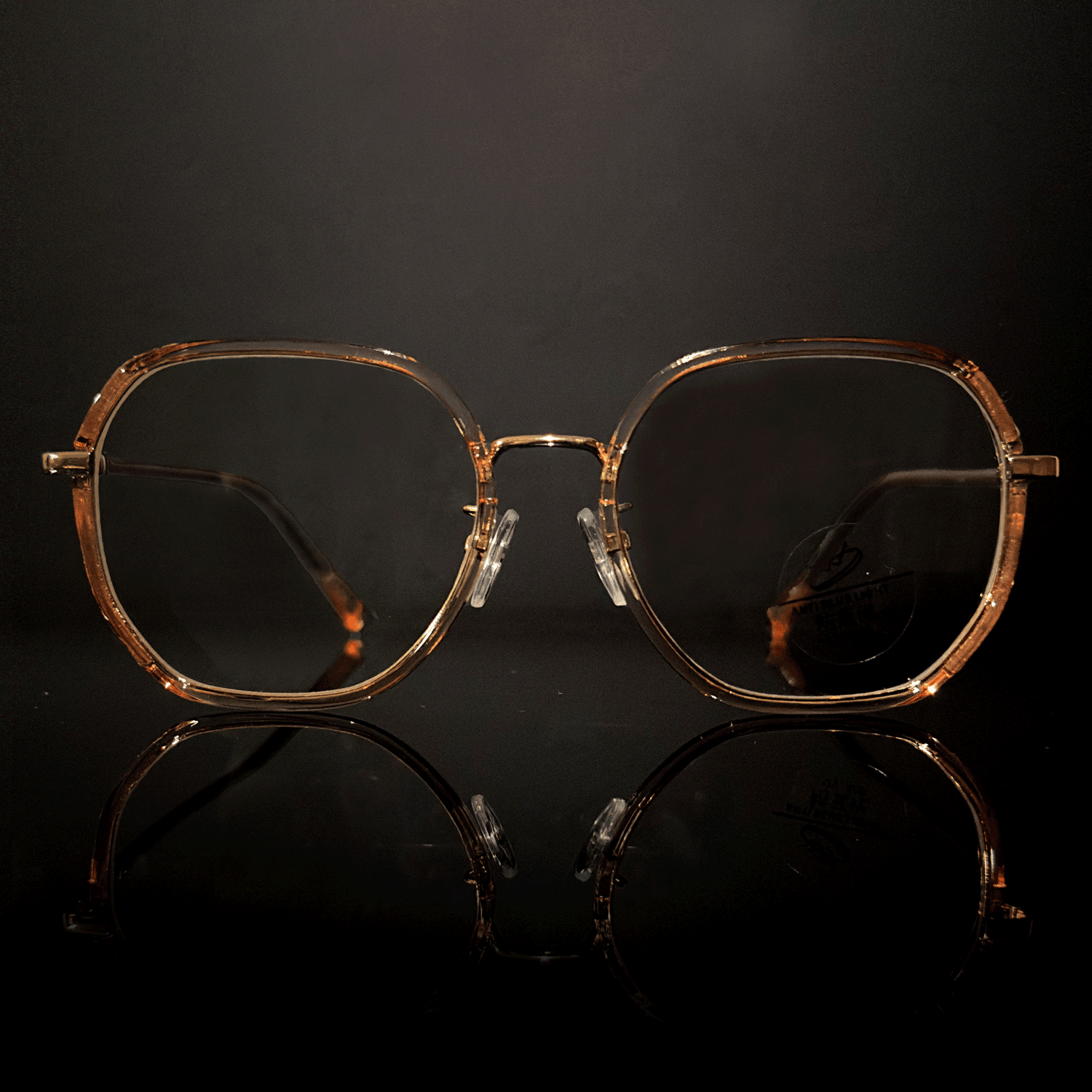 Vintage clear pink glittering prescription glasses on a reflective surface against a dark background.